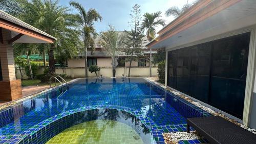 ein Pool neben einem Haus in der Unterkunft Cozy Villa Tai in Na Jomtien