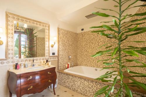 baño con bañera, lavabo y árbol en Villa il Mandorlo by VacaVilla en Passignano sul Trasimeno