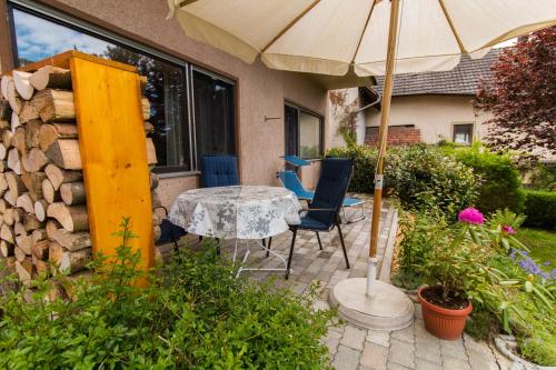 um pátio com uma mesa, cadeiras e um guarda-sol em Ferienwohnung Auer em Stockach