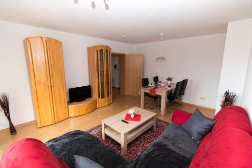 uma sala de estar com um sofá vermelho e uma mesa em Ferienwohnung Auer em Stockach