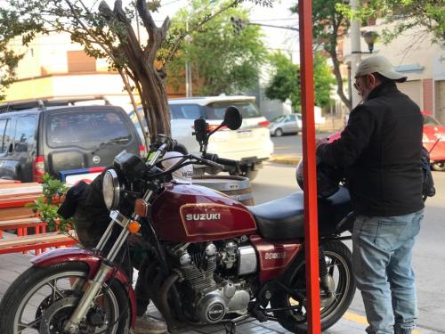 een man die naast een motor staat bij een benzinepomp bij Il Point Hostel Cafe in Neuquén