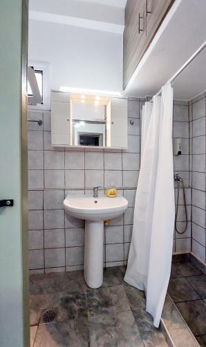 a bathroom with a sink and a white shower curtain at Harmony Cottage in Vasilikí