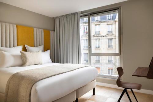 um quarto com uma cama e uma grande janela em Hôtel Pilgrim em Paris