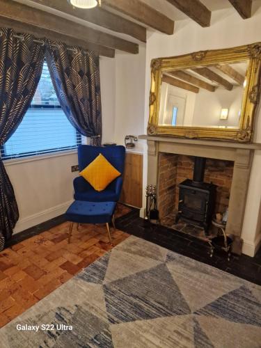 a living room with a blue chair and a fireplace at 2 Bed Cottage, Houghton on the Hill, Leicestershire 