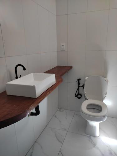 ein weißes Bad mit einem Waschbecken und einem WC in der Unterkunft Apartamento Brisa da Ilha in Cayru