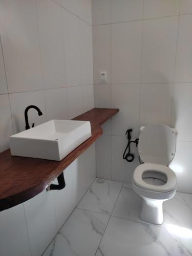 a white bathroom with a sink and a toilet at Ap Brisa da Ilha Boipeba in Cayru