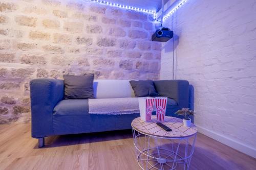 un canapé bleu dans une pièce avec une table dans l'établissement Le César Cinéma 10 mn Paris Gare de Lyon et 5 minutes RER, à Alfortville