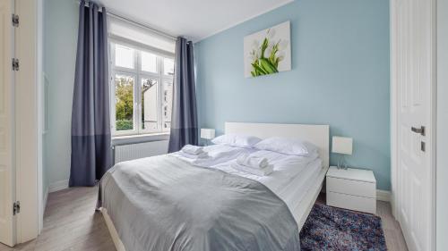 a bedroom with a bed with blue walls and a window at Apartamenty Sun & Snow Grunwaldzka in Sopot