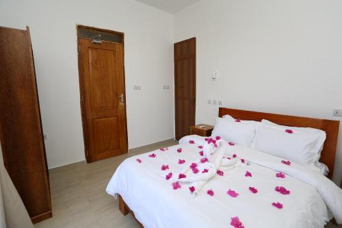 a bedroom with a white bed with pink flowers on it at IMARA VILLA 