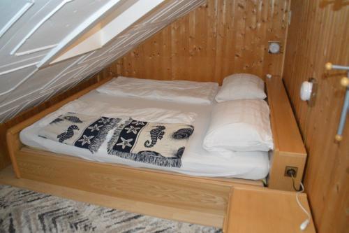 a bed in a wooden cabin with pillows on it at Ferienwohnung unterm Horn in Immenstadt im Allgäu