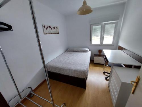 a small bedroom with a bed and a desk at Apartamento parque las llamas in Santander