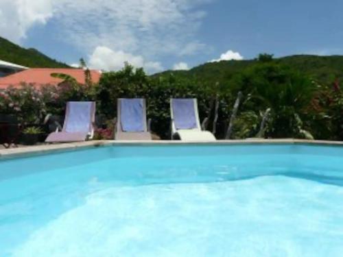una piscina con 3 sillas en Villa Piscine - Bougainvillier, en Les Anses-dʼArlet