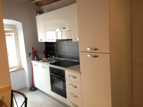 una cucina con armadi bianchi e un forno a piano cottura nero di Appartamento Porto Azzurro a Porto Azzurro