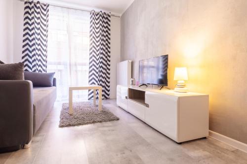 a living room with a television on a white cabinet at RentPlanet - Apartamenty Leśny Dom in Karpacz