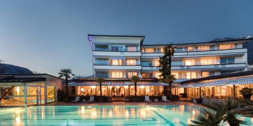 a hotel with a swimming pool in front of a building at Parkhotel Delta, Wellbeing Resort in Ascona