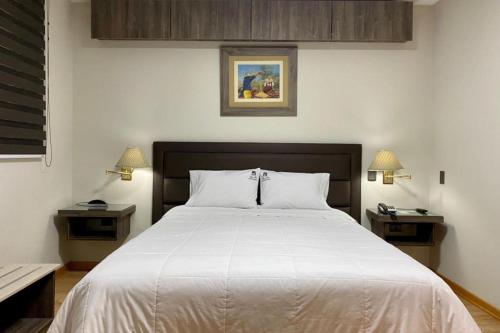 um quarto com uma grande cama branca e duas mesas em FABRIZIO GUEST HOUSE em Cusco