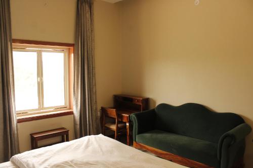 1 dormitorio con silla verde y ventana en Farm Aavjo, en Pushkar