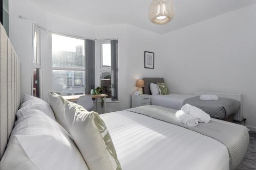 a white bedroom with two beds and a window at Host Liverpool - Anfield Gem, pet-friendly with garden in Liverpool