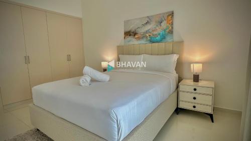 a bedroom with a large white bed and a night stand at Calm Chaos 4 BR Villa with maid Room in Damac Hills 2 By Bhavan Vacation Homes in Dubai