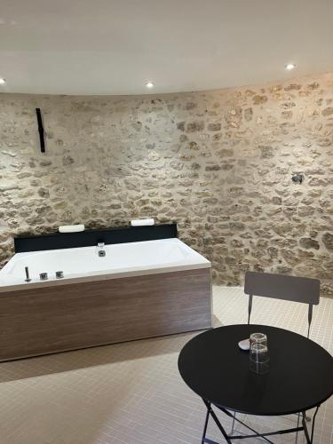 a bath tub in a room with a table and a chair at Ferme de Mesangeon in Beauvilliers
