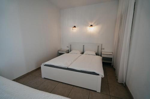 een witte slaapkamer met 2 bedden en 2 lampen bij El Libre - Ocean View Apartment in Puerto Rico de Gran Canaria