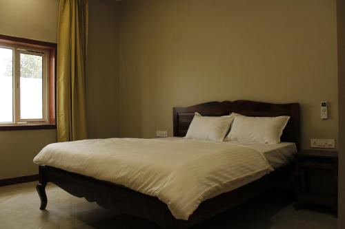 Una cama con sábanas blancas y almohadas en un dormitorio en Farm Aavjo, en Pushkar