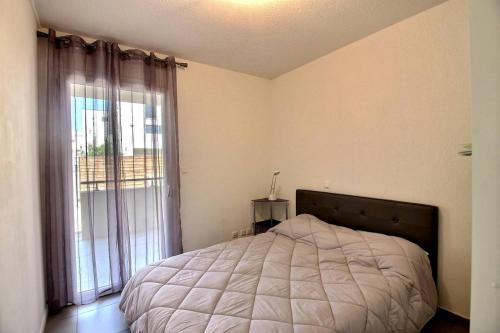 une chambre avec un lit et une grande fenêtre dans l'établissement Perra, à Sérignan