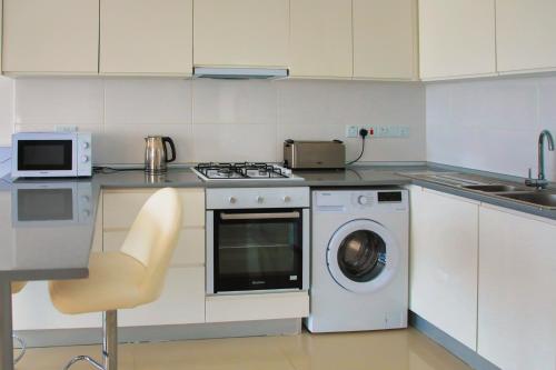 a kitchen with a washing machine and a microwave at Superior One Bedroom Apartment in Caesar Resort & SPA, Long Beach in Perivolia tou Trikomou