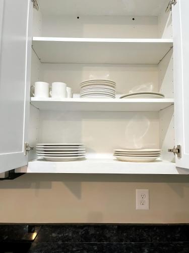a white cabinet with plates and dishes in it at Ideal Location Spacious in Wilson