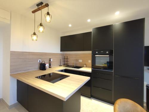 a kitchen with black cabinets and a counter top at L'Ipanema - Standing T2 + Balcon in Cassis