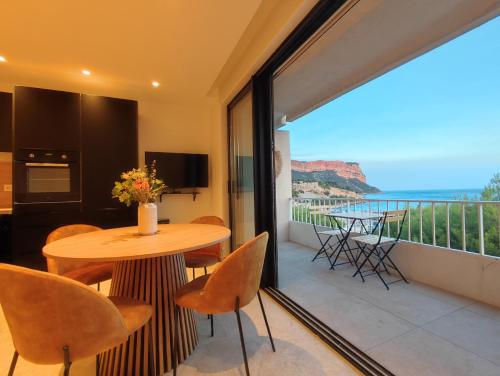 a room with a table and chairs and a balcony at L'Ipanema - Standing T2 + Balcon in Cassis