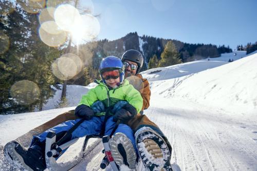 two people sitting on a sled in the snow at Haus Edelweiss in Brand