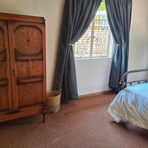 a bedroom with a bed and a dresser and a window at Bloom in Bloemfontein