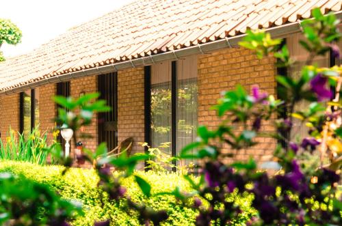 a brick house with windows and flowers in the foreground at Hotel Pacific in Weelde
