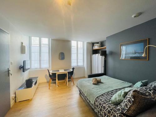 1 dormitorio con cama, escritorio y mesa en Résidence Maréchaux, en Saint-Jean-dʼAngély