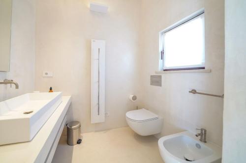 a white bathroom with a toilet and a sink at Masseria Tenute Emera By Raro Villas in Lizzano