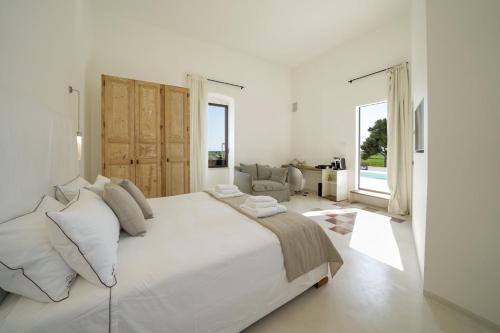 a white bedroom with a large bed and a living room at Masseria Tenute Emera By Raro Villas in Lizzano