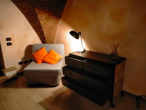 1 dormitorio con silla, lámpara y cómoda en AL LOFT, Centro Storico en Prato