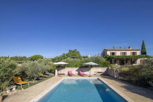 une piscine avec des chaises et des parasols ainsi qu'une maison dans l'établissement Mas de Lavande, à Saint-Rémy-de-Provence