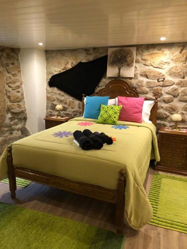 una camera da letto con un grande letto con cuscini colorati di Casas do Lobo a Tarouca