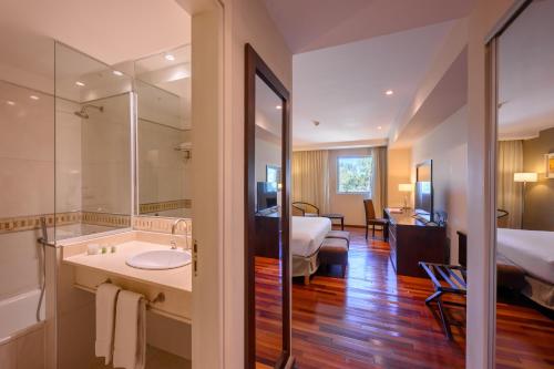 um quarto de hotel com casa de banho e um quarto em Orfeo Suites Cordoba em Córdoba