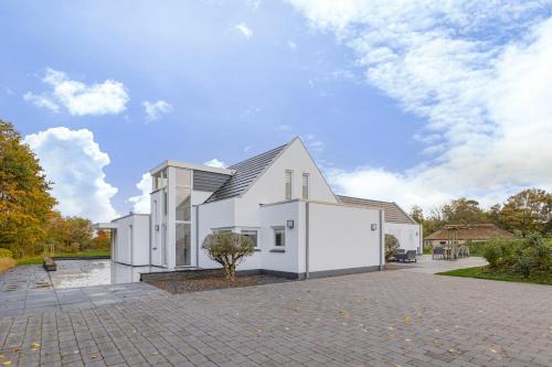 a white house with a tree in a driveway at Landgoed Hermitage - Villa Minerva - XXL Zwemspa - max 16 personen in Ouddorp