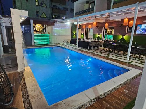 a large blue swimming pool with a restaurant in the background at Suna' a Home Bonapriso in Douala