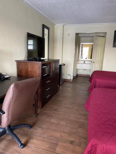 ein Hotelzimmer mit einem Schreibtisch, einem Bett und einem TV in der Unterkunft Driftwood Inn - Lake City in Lake City