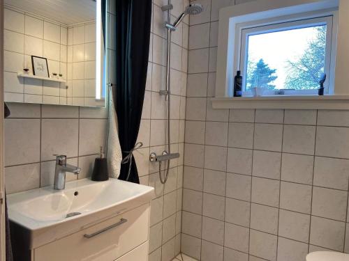 a bathroom with a sink and a shower with a window at Holiday home Fanø VIII in Fanø
