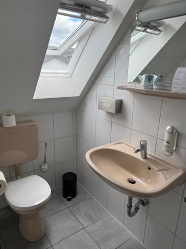 a bathroom with a sink and a toilet and a skylight at Schröders Gästehaus in Langstedt