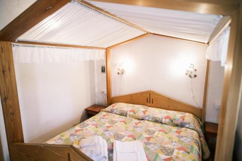 a small bedroom with a bed with a canopy at Chalet Maso Pino in Castello Tesino