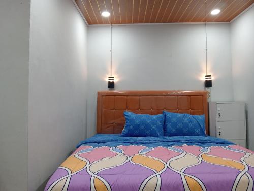 a bedroom with a bed with two lights above it at Vulkaan Homestay in Berastagi
