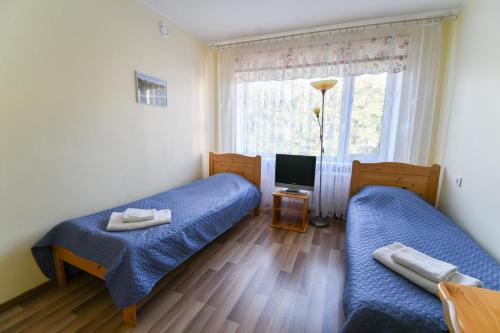 mały pokój z 2 łóżkami i telewizorem w obiekcie Hostel Nele w mieście Jõhvi