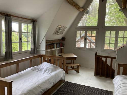 a bedroom with a bed and a desk and windows at Clos Normand in Varengeville-sur-Mer